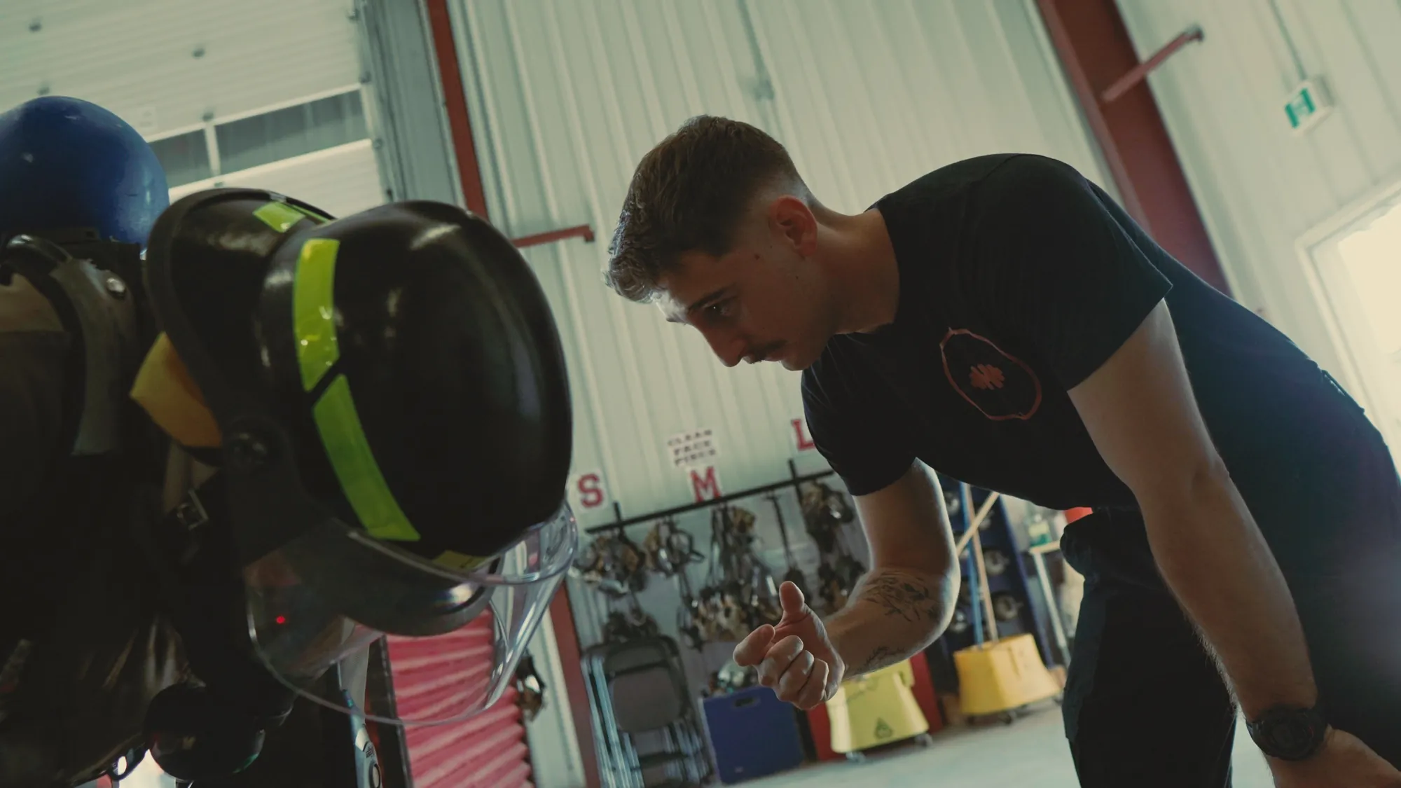 Cole Zon coaching beside racked helmets and SCBA gear at the fire hall